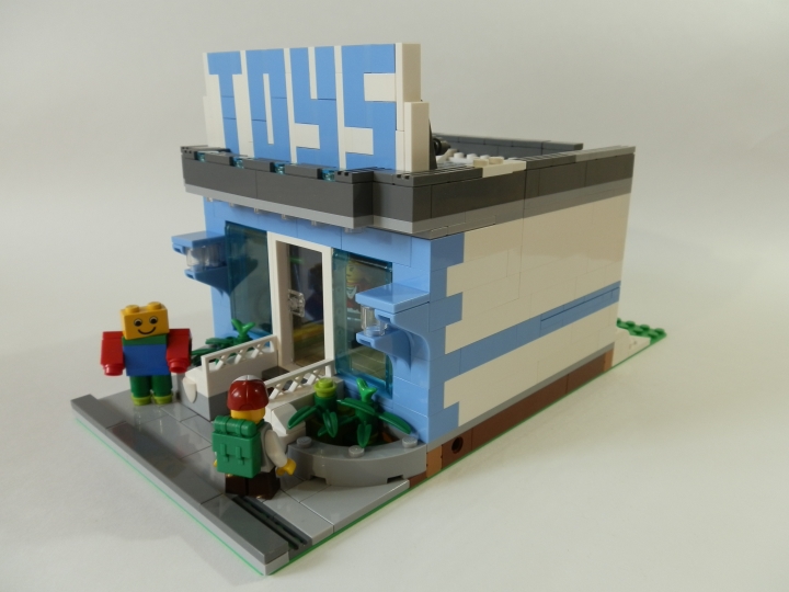 LEGO MOC - Новогодний Кубик 2014 - Магазин игрушек.: Магазин-то модульный. Наверняка стоит на какой-нибудь оживлённой улице между другими домами и магазинами. Перед входом стоит человек в костюме, эдакая живая реклама. И ребёнок, который засмотрелся на что-то в витрине магазина.