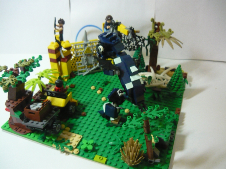 LEGO MOC - Мир Юрского периода - Атака разъяренного динозавра на лагерь охотников.: Общий вид работы. Вы можете рассмотреть всю композицию. Видим, что динозавр ломая деревья пробирается к базе, к которой так же спешит внедорожник. Всё это происходит в джунглях.