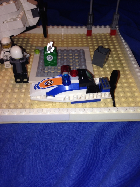 LEGO MOC - Погружение - Школа навигации батискафов (2050г.): Катер полицейского похож на пиранью, а слева стоит полицейский и пишет протокол. Рядом сидит пострадавший аквалангист, который просто плыл мимо.
